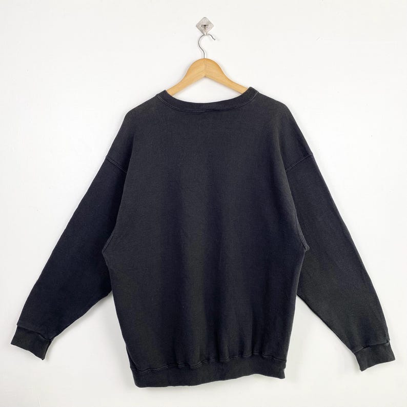 Puede incluir: Una sudadera negra de manga larga con cuello redondo.