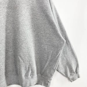 May include: A heather gray sweatshirt with a crew neck and long sleeves. The garment is made of a soft, textured fabric. The cuffs and hem are ribbed. The sweatshirt is a casual, comfortable style.