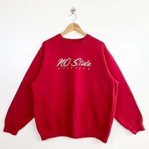 May include: Red sweatshirt with a white "NC State Wolfpack" logo.