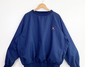 May include: Navy blue pullover windbreaker with a small embroidered design on the chest. The windbreaker has a crew neck, long sleeves, and a banded waist and cuffs. The design appears to be a golf-themed emblem.