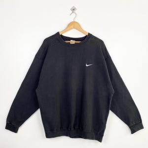 Puede incluir: Sudadera Nike negra con un logotipo Swoosh blanco en el pecho.