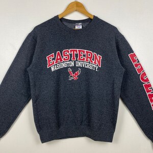 May include: A grey sweatshirt with the words "Eastern Washington University" in red and white lettering. The university's mascot, an eagle, is also printed on the front of the sweatshirt. The word "Eagles" is printed in red on the right sleeve.