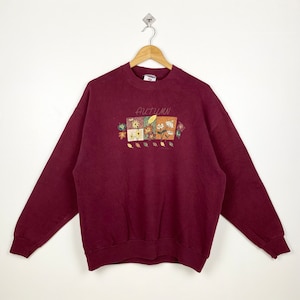 May include: A maroon sweatshirt with a graphic of autumn leaves and flowers. The text "AUTUMN" is printed on the front of the sweatshirt.