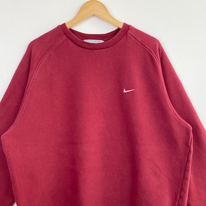 May include: A red crew neck sweatshirt with a white Nike swoosh logo on the left chest.