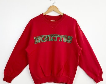 May include: Red sweatshirt with a green and white Benetton logo.