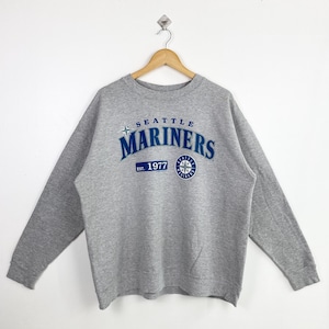May include: Gray sweatshirt with a blue and white Seattle Mariners logo. The logo says "Seattle Mariners" and "Est. 1977".