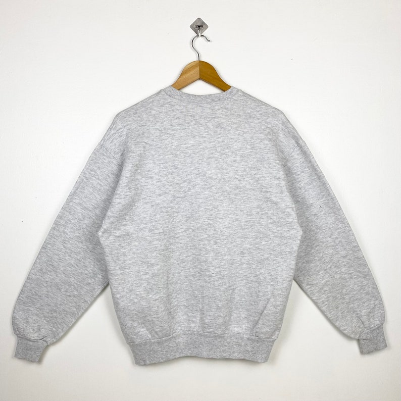 K&ouml;nnte beinhalten: Ein grauer Pullover mit Rundhalsausschnitt und langen &Auml;rmeln.