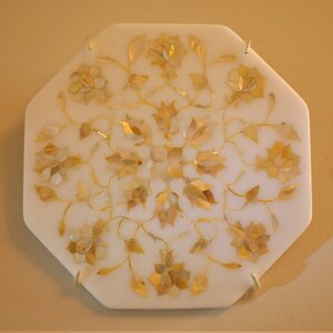 May include: A white octagonal marble tray with a floral design inlaid with mother of pearl and gold accents.
