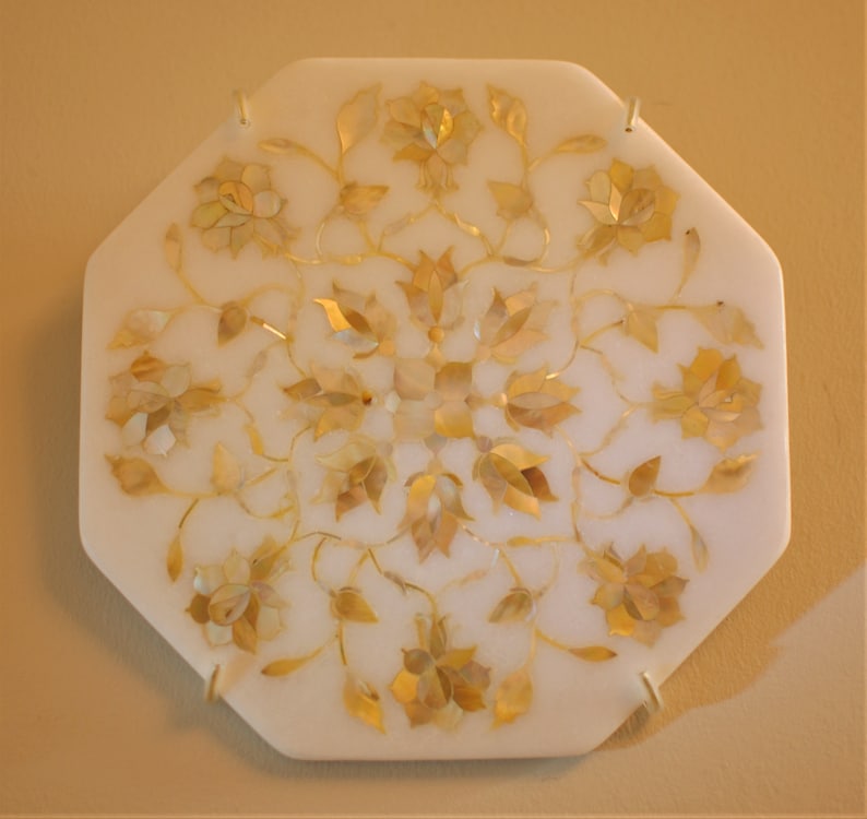 May include: A white octagonal marble tray with a floral design inlaid with mother of pearl and gold accents.