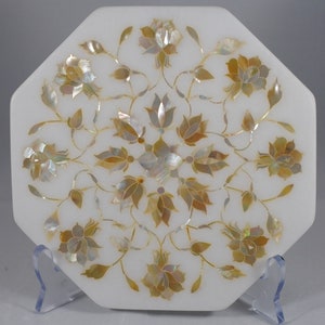 May include: White marble octagonal tray with a floral design inlaid with mother of pearl. The design features a central motif of a flower with eight petals surrounded by smaller flowers and leaves.
