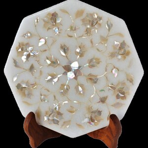 May include: White octagonal marble tray with intricate floral design inlaid with iridescent mother of pearl. The tray is on a wooden stand.