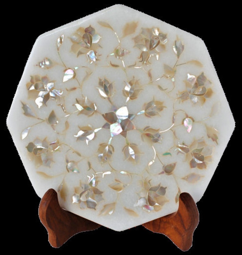 May include: White octagonal marble tray with intricate floral design inlaid with iridescent mother of pearl. The tray is on a wooden stand.