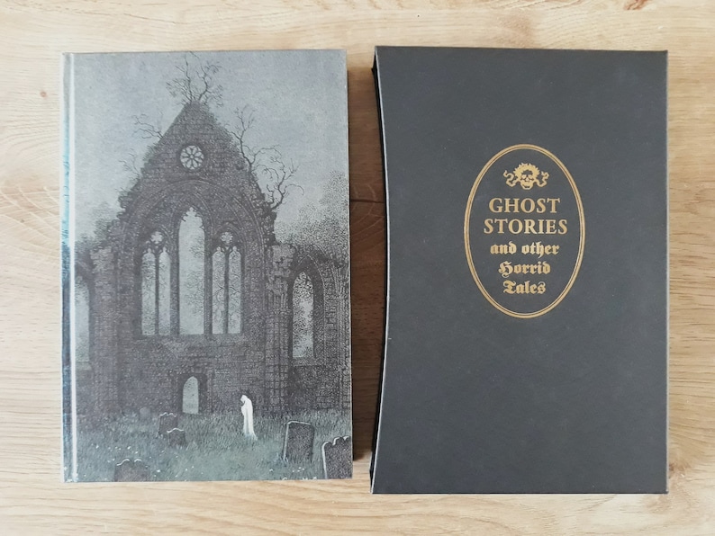 K&ouml;nnte beinhalten: Ein schwarzes Hardcover-Buch mit goldfarbenem R&uuml;cken und Titel. Der Titel lautet "Ghost Stories and other Horrid Tales". Das Coverbild ist eine Schwarzwei&szlig;illustration einer gotischen Kirche.