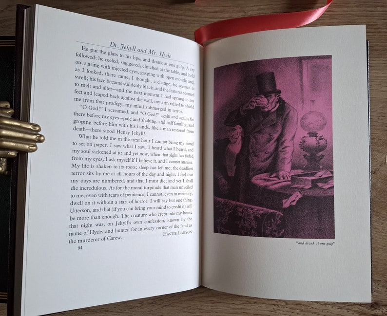 Pu&ograve; includere: Un primo piano di un libro aperto con un'illustrazione in bianco e nero di un uomo con un cappello a cilindro e un cappotto. L'uomo tiene un bicchiere e lo guarda. Il testo sulla pagina dice "Dr. Jekyll and Mr. Hyde" e "and drank at one gulp."