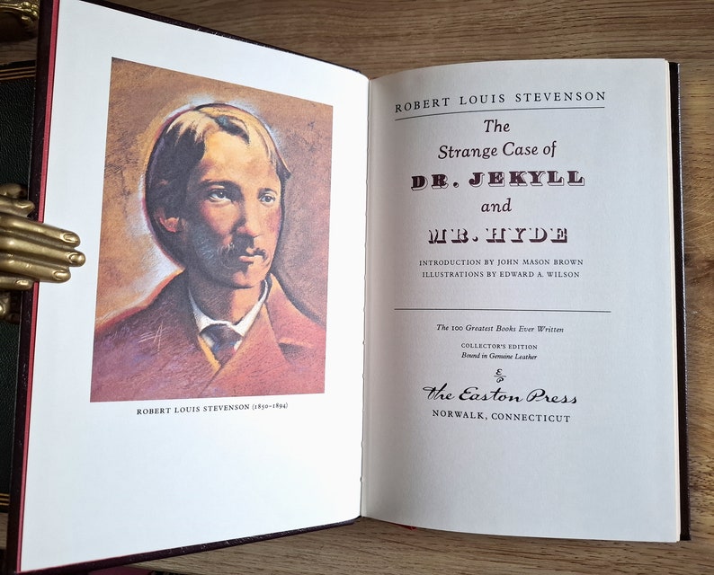 Pu&ograve; includere: Un libro vintage rilegato in pelle intitolato "Lo strano caso del dottor Jekyll e Mr. Hyde" di Robert Louis Stevenson. Il libro fa parte di una serie di edizioni da collezione, "I 100 migliori libri mai scritti", e presenta un'illustrazione dell'autore sulla copertina.