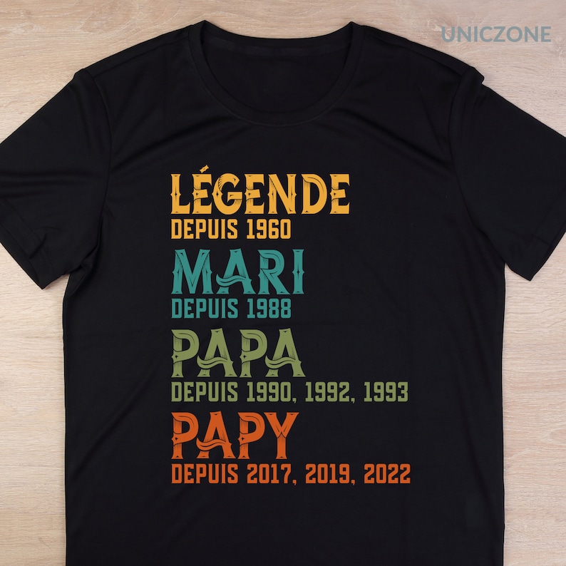 K&ouml;nnte beinhalten: Schwarzes T-Shirt mit einer Grafik im Vintage-Stil, die "L&Eacute;GENDE DEPUIS 1960 MARI DEPUIS 1988 PAPA DEPUIS 1990, 1992, 1993 PAPY DEPUIS 2017, 2019, 2022" lautet.