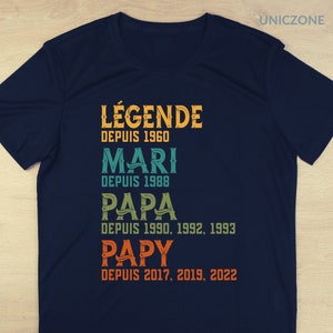 K&ouml;nnte beinhalten: Ein marineblaues T-Shirt mit einem Vintage-Design, auf dem "L&Eacute;GENDE DEPUIS 1960 MARI DEPUIS 1988 PAPA DEPUIS 1990, 1992, 1993 PAPY DEPUIS 2017, 2019, 2022" steht.