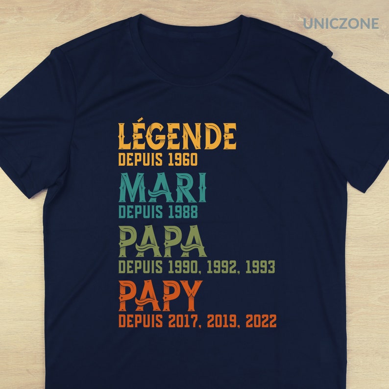 K&ouml;nnte beinhalten: Ein marineblaues T-Shirt mit einem Vintage-Design, auf dem "L&Eacute;GENDE DEPUIS 1960 MARI DEPUIS 1988 PAPA DEPUIS 1990, 1992, 1993 PAPY DEPUIS 2017, 2019, 2022" steht.