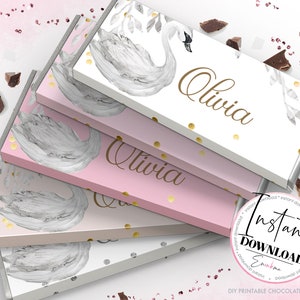 May include: Printable chocolate bar wrappers featuring a watercolor swan design with gold glitter accents. The wrappers are pink and white and say "Olivia" on them.  DIY printable chocolate wrappers.