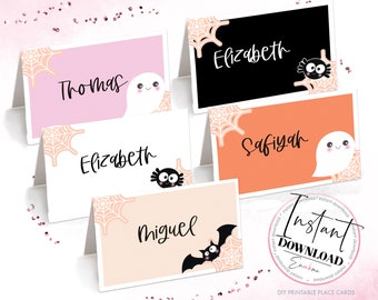 May include: Printable Halloween place cards with spider web designs and cute ghost and bat illustrations. The names Thomas, Elizabeth, Safiyah, and Miguel are written on the cards.