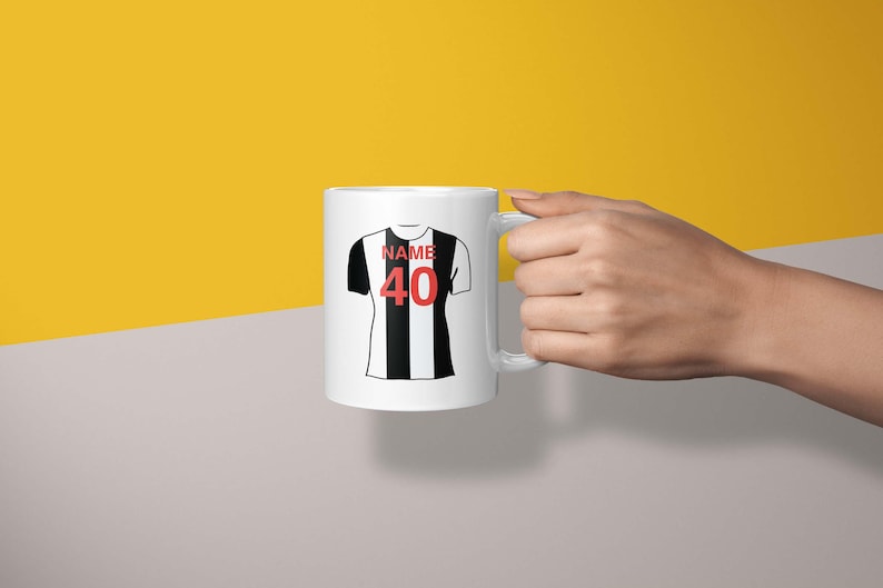 May include: White ceramic mug with a black and white striped football jersey design. The jersey has the word "NAME" and the number "40" printed on it.