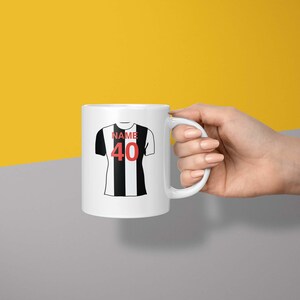 May include: White ceramic mug with a black and white football jersey design. The jersey has the word "NAME" and the number "40" printed on it.
