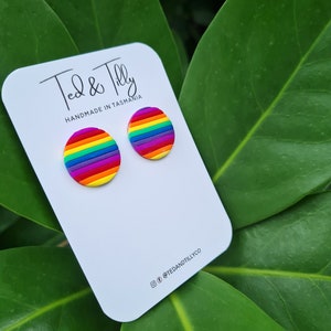 Op de afbeelding: Een paar regenboogkleurige oorbel studs op een witte kaart met de tekst "Ted & Tilly Handmade in Tasmania" en de social media handle "@tedandtillyco".