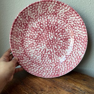 May include: A large, round, white ceramic serving bowl with a pink speckled pattern.