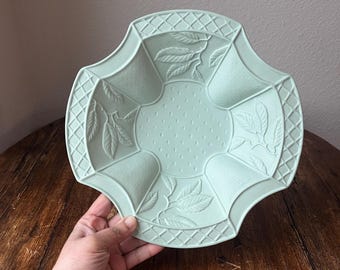 May include: A light green ceramic serving bowl with a raised design of leaves and a lattice pattern around the edge.