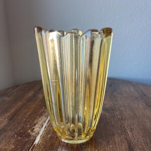 May include: A yellow glass vase with a fluted design and a scalloped rim.