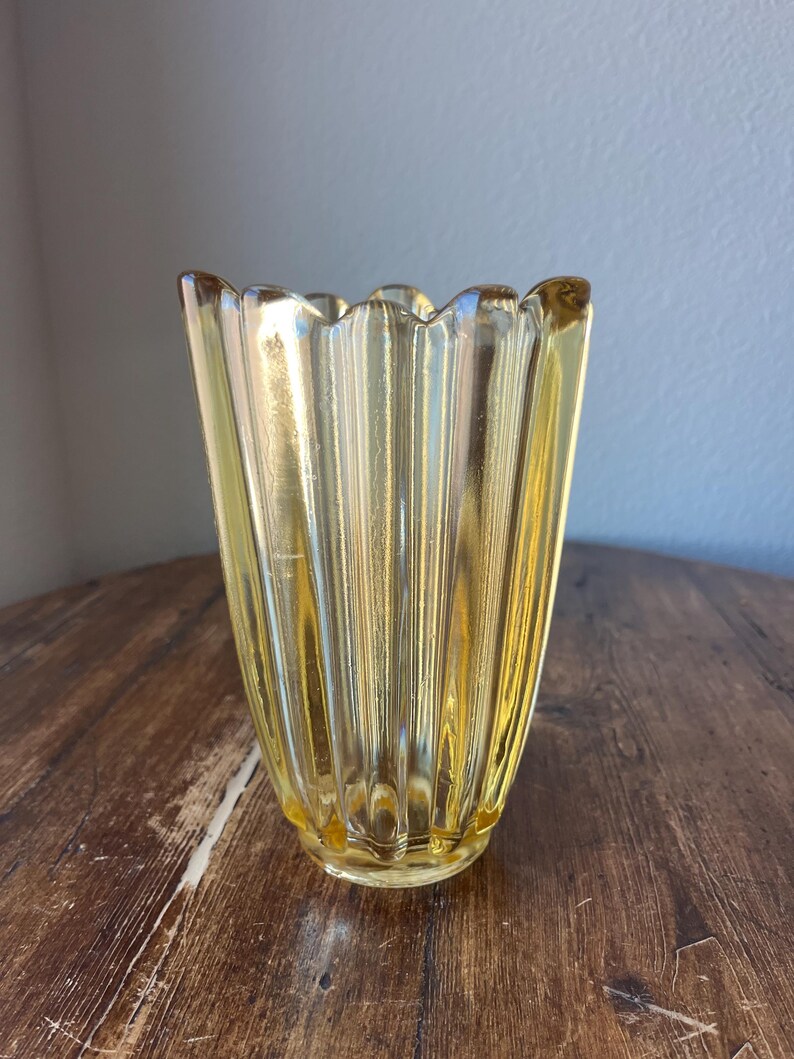 May include: A yellow glass vase with a fluted design and a scalloped rim.