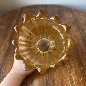 May include: A clear amber glass vase with a fluted design and a scalloped rim.