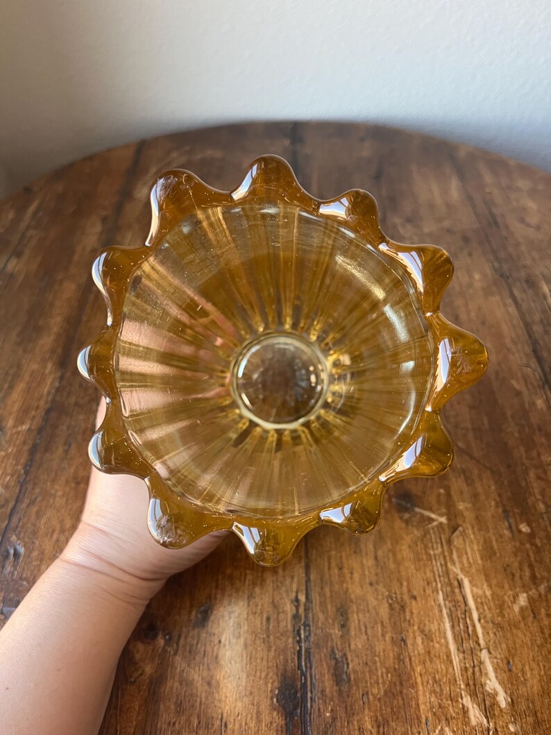 May include: A clear amber glass vase with a fluted design and a scalloped rim.