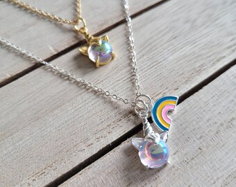 May include: Two silver necklaces with iridescent unicorn charms. One necklace has a rainbow charm attached to the unicorn charm.