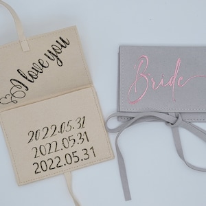 May include: Two small fabric pouches with a ribbon tie. One pouch is beige and says "I love you" and "2022.05.31" on the inside. The other pouch is gray and says "Bride" in pink lettering.