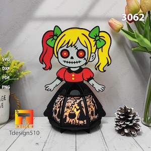 May include: A Halloween lantern with a cartoon zombie girl design. The girl has yellow hair, red eyes, and a black dress. The lantern has a black frame with a witch silhouette design. The number 3062 is visible.