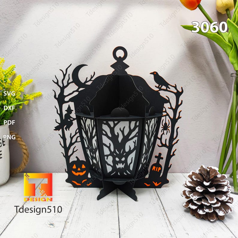 May include: A black Halloween lantern with a spooky design. The lantern features a witch, a crow, a spider, a jack-o'-lantern, and a tombstone. The lantern has the number 3060 on the top right. The text "Tdesign510" is visible.
