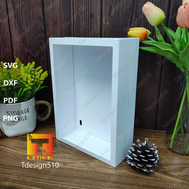 May include: A white, rectangular shadow box with a recessed interior. The box is made of wood and has a clean, modern design. The image includes the text "SVG, DXF, PDF, PNG, STORAGE, Tdesign510".