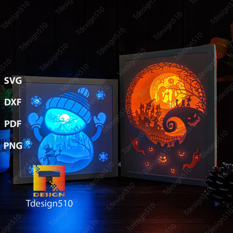 May include: Two illuminated shadow box art pieces. One features a snowman in a blue hat and mittens, the other a Halloween scene with a full moon and spooky silhouettes. The text "Tdesign510" is visible.