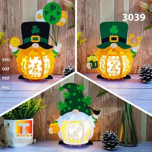Puede incluir: Un conjunto de tres diseños de gnomos cortados con láser para manualidades. Los gnomos llevan sombreros verdes con tréboles y sostienen una jarra de cerveza, una herradura y una pipa. Los gnomos están frente a un fondo de madera. El número de diseño 3039 es visible en la esquina superior derecha.