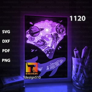 May include: A white frame with a purple and blue glow, featuring a whale with an astronaut and planets inside. The frame has the text "Tdesign510" and the number "1120" on it.