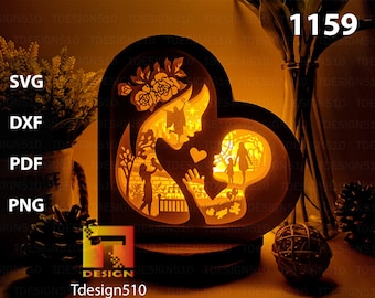 May include: A heart-shaped, layered paper art piece with a mother and child theme. The design features silhouettes of a mother and child, flowers, and other figures. The text "1159", "SVG", "DXF", "PDF", "PNG", and "Tdesign510" are visible.
