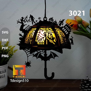 May include: A black metal Halloween-themed hanging lamp shaped like an umbrella with a spider, bats, and a grim reaper design. The lamp has a yellow light shining through the cut-out design. The text "3021" is visible in the upper right corner of the image.