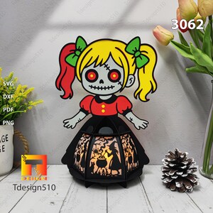 May include: A Halloween lantern with a cartoon zombie girl design. The girl has yellow hair, red eyes, and a black dress. The lantern has a black frame with a witch silhouette design. The number 3062 is visible.
