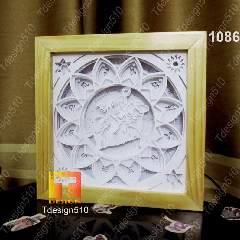 May include: A white papercraft 3D art piece in a wooden frame. The design features a zodiac symbol with a constellation and a flower-like design around it. The zodiac symbol is Sagittarius.