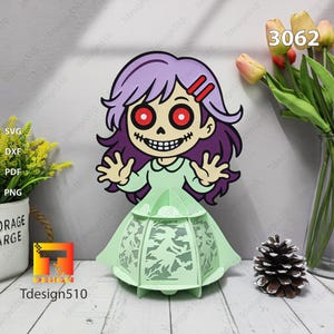 May include: A Halloween papercraft of a cartoon zombie girl with purple hair and red eyes, wearing a green dress. She stands before a light green lantern with a bat design. The image includes the text "Tdesign510" and the number "3062".