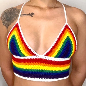 May include: A rainbow crochet top with a white crocheted halter strap. The top is made with a variety of colors, including red, orange, yellow, green, blue, indigo, and violet.