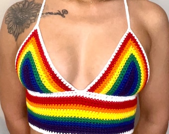 May include: A rainbow crochet top with a white crocheted halter strap. The top is made with a variety of colors, including red, orange, yellow, green, blue, indigo, and violet.