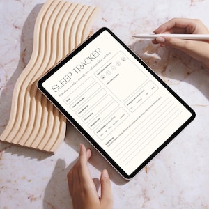 Op de afbeelding: Een digitale tablet met een witte achtergrond en zwarte tekst toont een slaaptrackerformulier. Het formulier bevat secties voor datum, tijd, slaap kwaliteit, energieniveaus en stemming bij het wakker worden. De tablet ligt op een houten oppervlak.