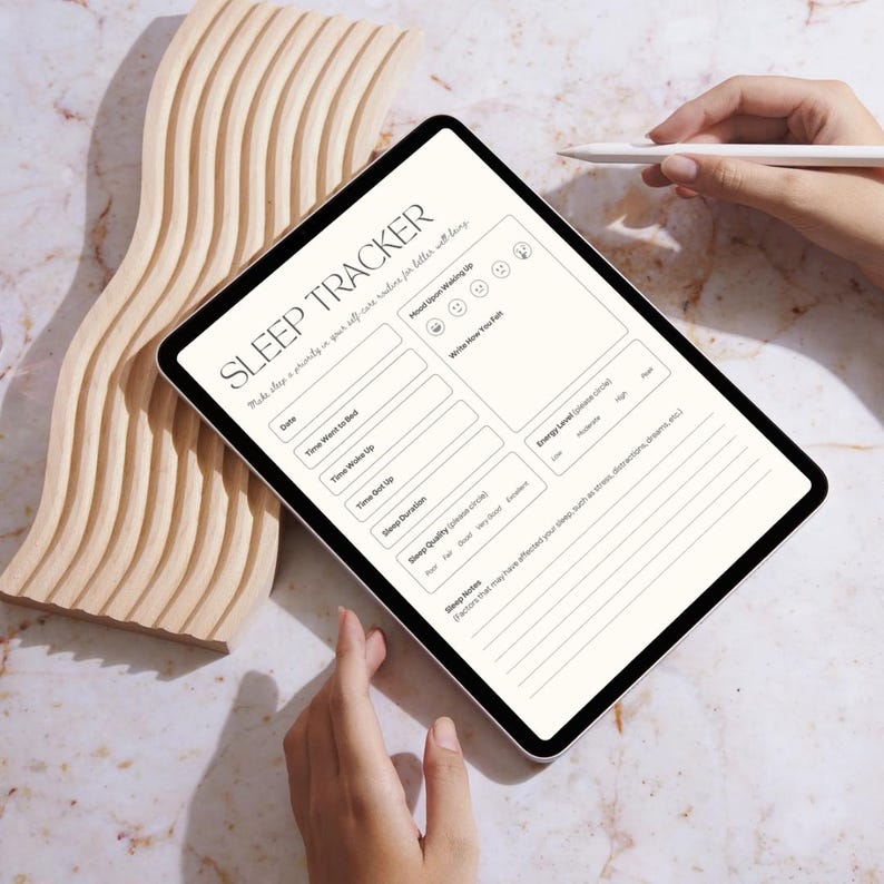 Op de afbeelding: Een digitale tablet met een witte achtergrond en zwarte tekst toont een slaaptrackerformulier. Het formulier bevat secties voor datum, tijd, slaap kwaliteit, energieniveaus en stemming bij het wakker worden. De tablet ligt op een houten oppervlak.